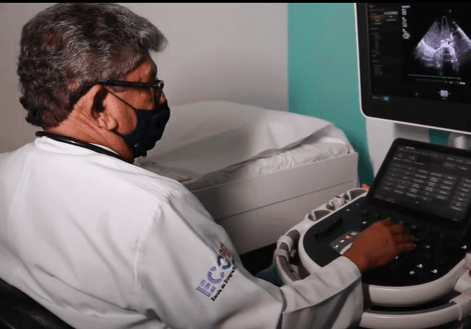 Medical professional operating an ultrasound machine with the screen displaying an ultrasound image.